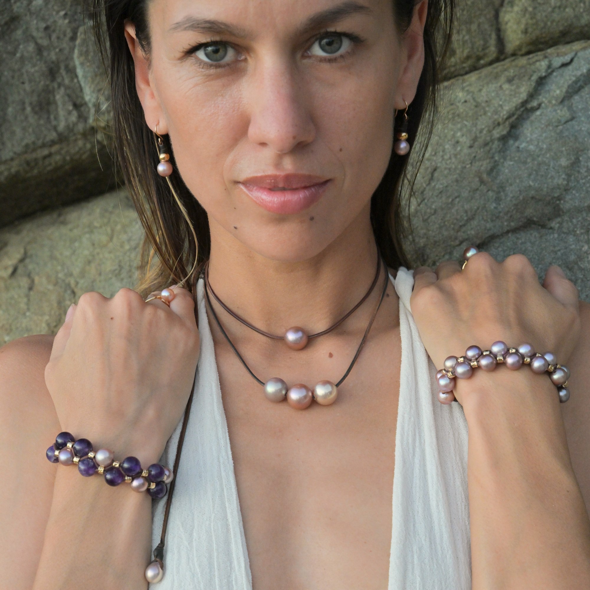 Boucles d’oreilles en cuir, perles roses, billes dorées et crochets en or, vue portée avec plusieurs colliers et bracelets, portrait de face.