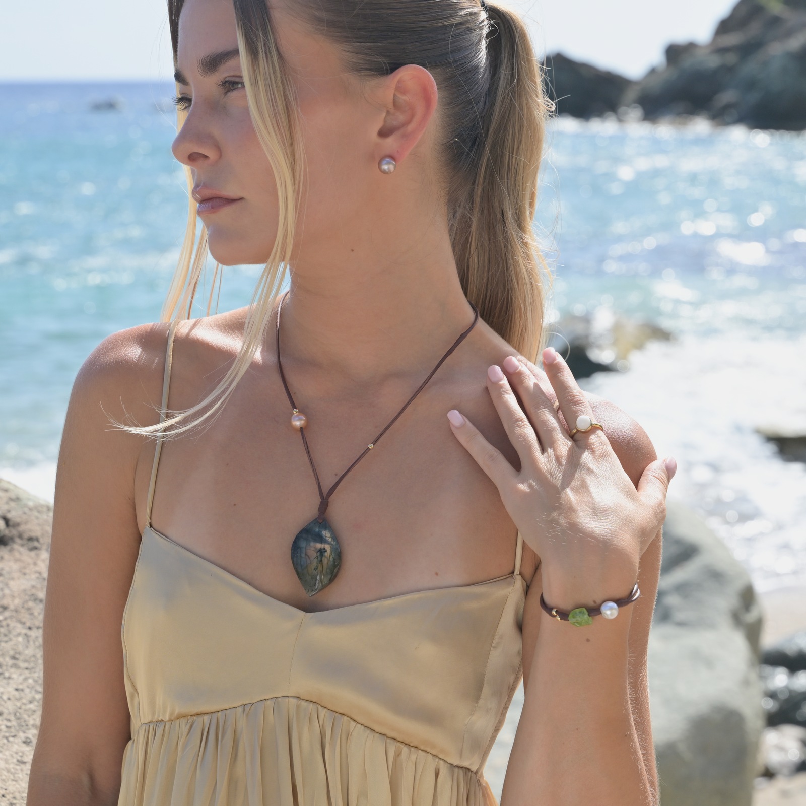 Clous en or 18 carats et perles roses d’eau douce, vue portée en bord de mer, avec une robe jaune.