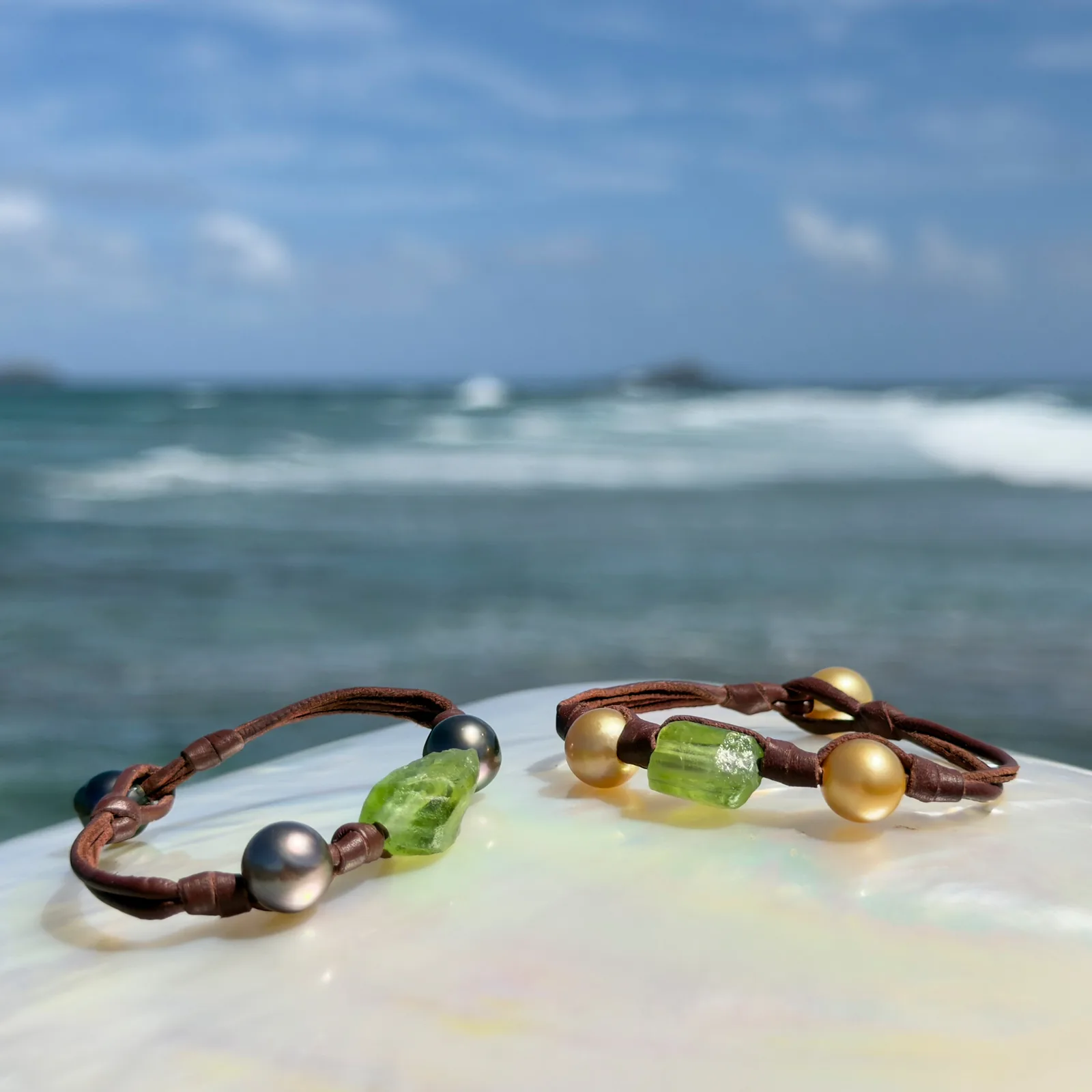 Bracelet en cuir, péridot et deux perles, deux variantes réunies, sur un coquillage.