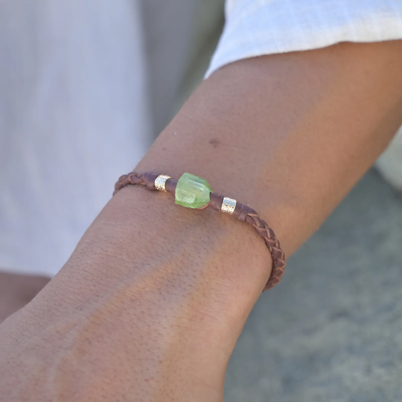 Bracelet en cuir tressé, péridot et tubes plaqués or, porté au poignet. Vue 4.