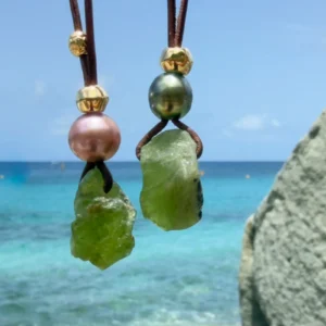 Leather necklace with a peridot pendant and a pearl, two variants shown together, hanging freely.