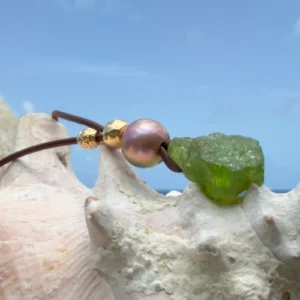 Leather necklace with a peridot pendant and a pearl, pink pearl, on a shell.