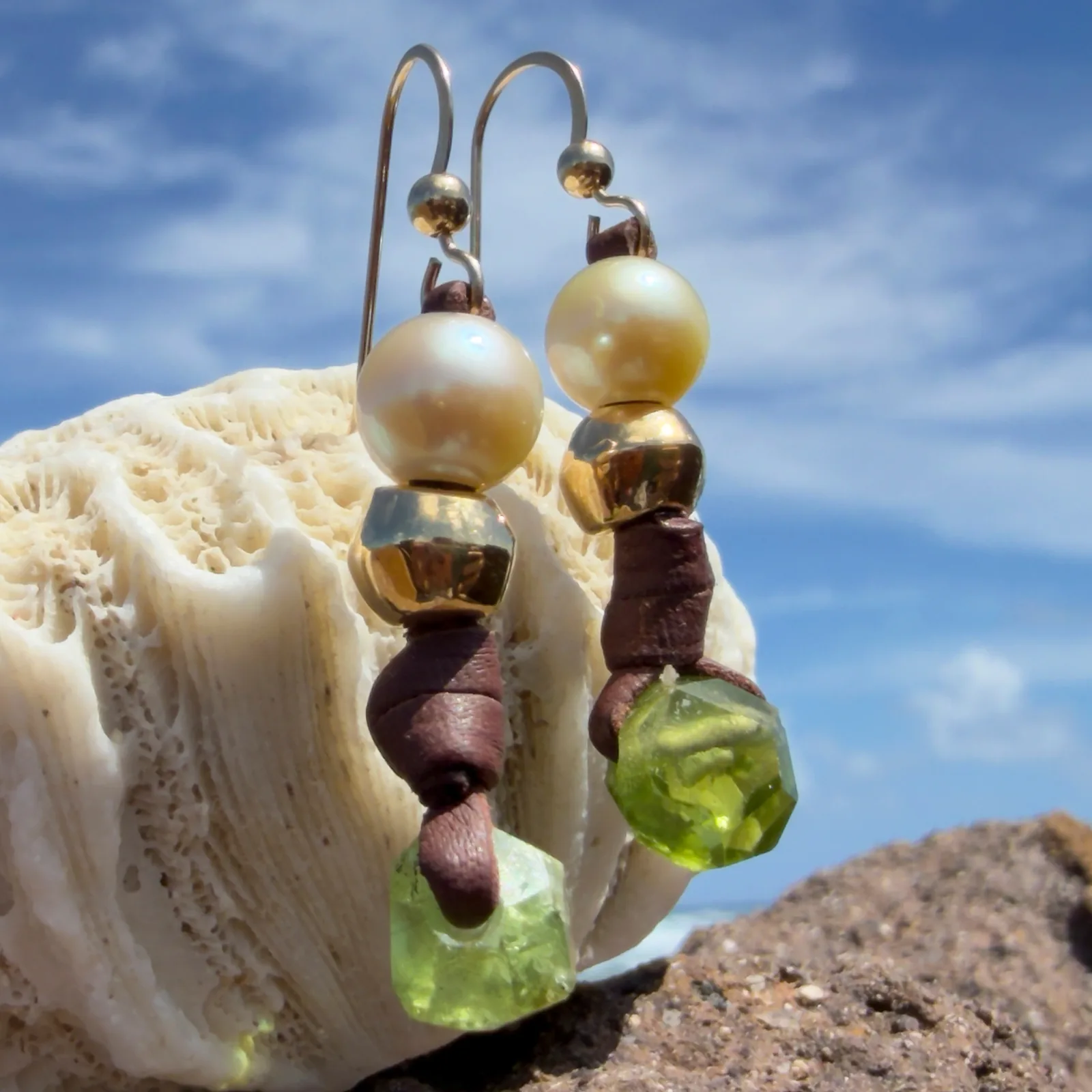 Boucles d’oreilles en cuir, perles des mers du Sud et péridot, sur un support de corail.