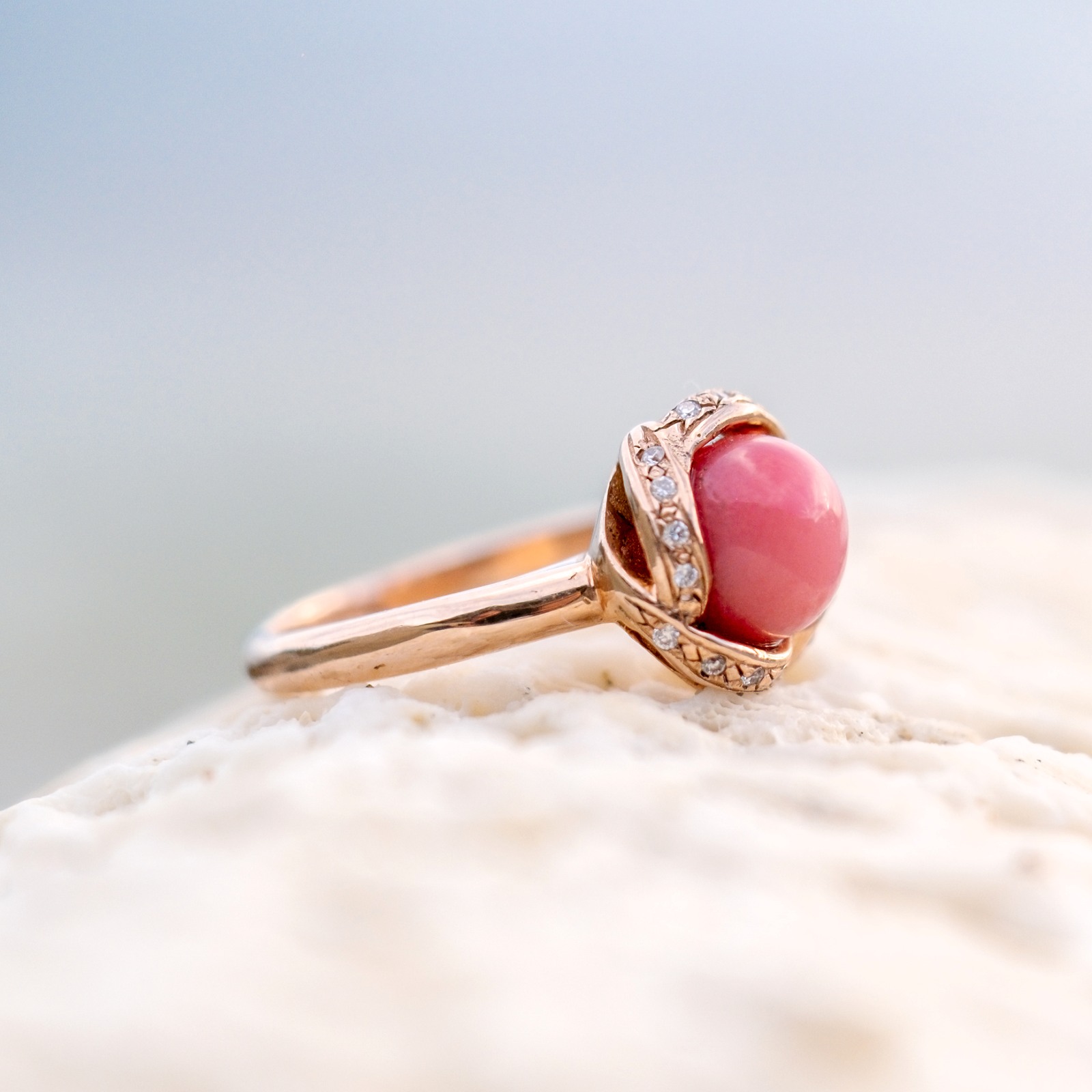 Bague en or rose, perle de lambis et diamants, posée sur du corail, autre côté de la monture.