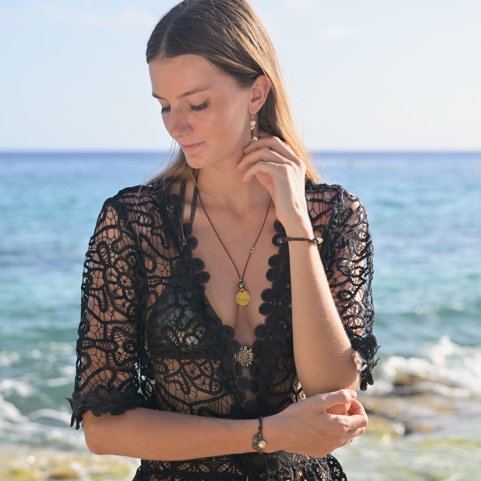 Leather pendant necklace with a gold escudo and a Tahitian pearl, worn view.