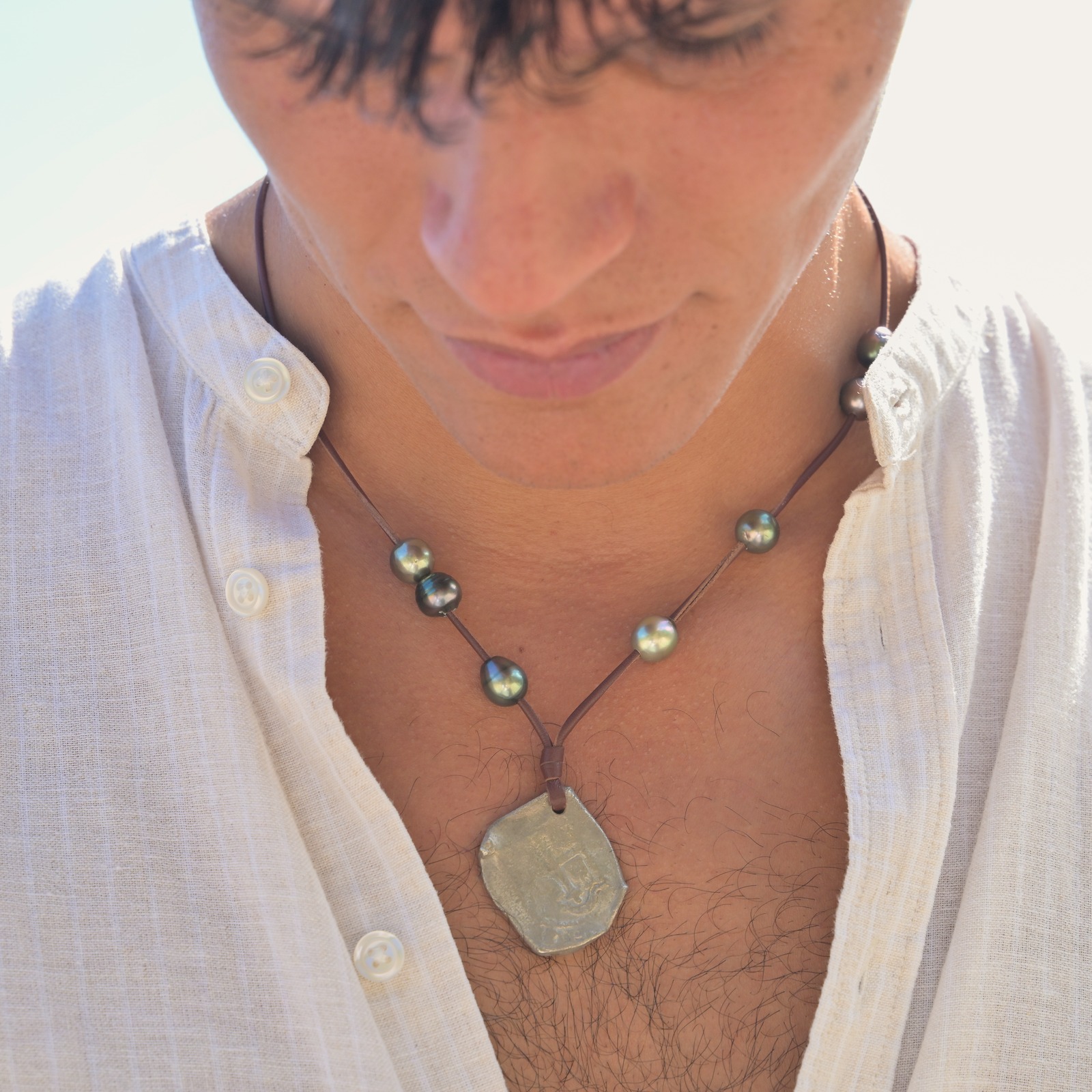 Pendant necklace with an eight-reales coin and Tahitian pearls, worn view.