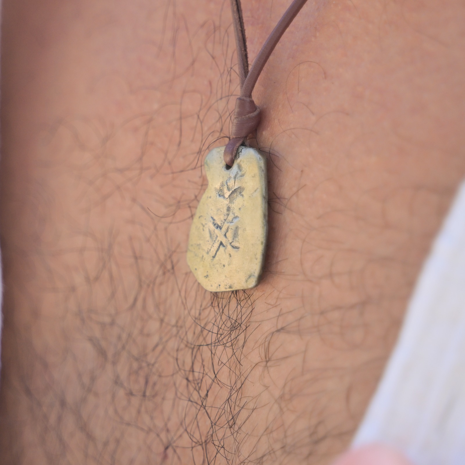Leather pendant necklace with a four-reales coin, close-up on the model.