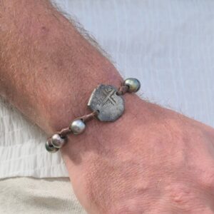 Bracelet en cuir, monnaie de 4 réaux et 6 perles de Tahiti, monnaie et perles au poignet.