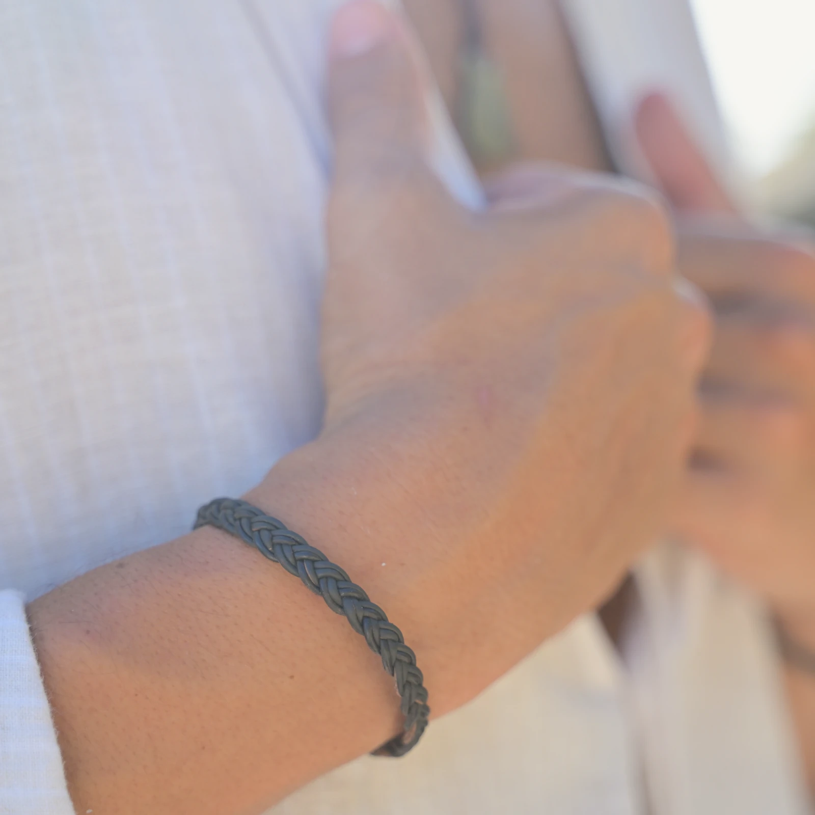 Braided Leather Bracelet with a Tahitian Pearl Clasp, worn on the wrist.
