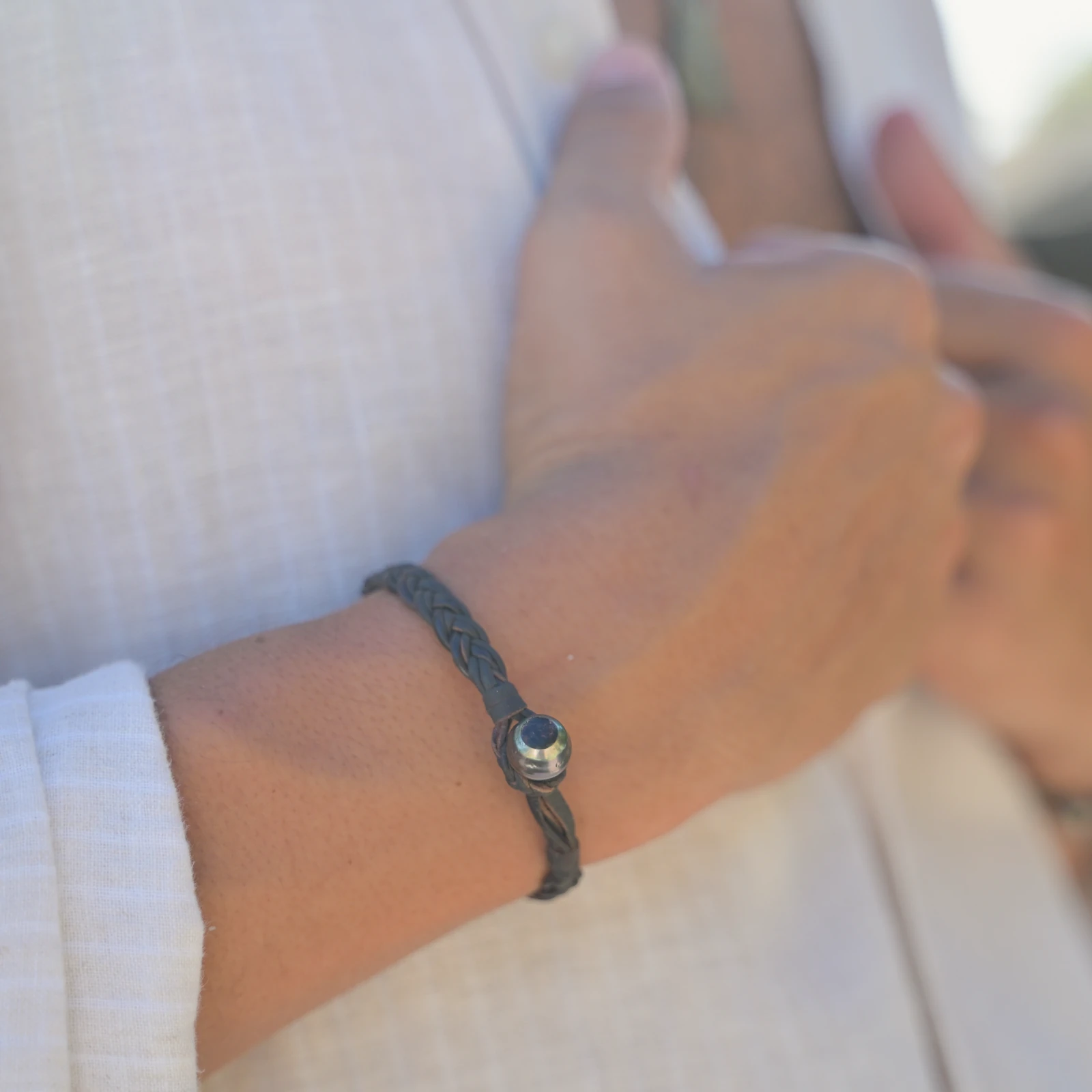 Braided Leather Bracelet with a Tahitian Pearl Clasp, worn on the wrist.