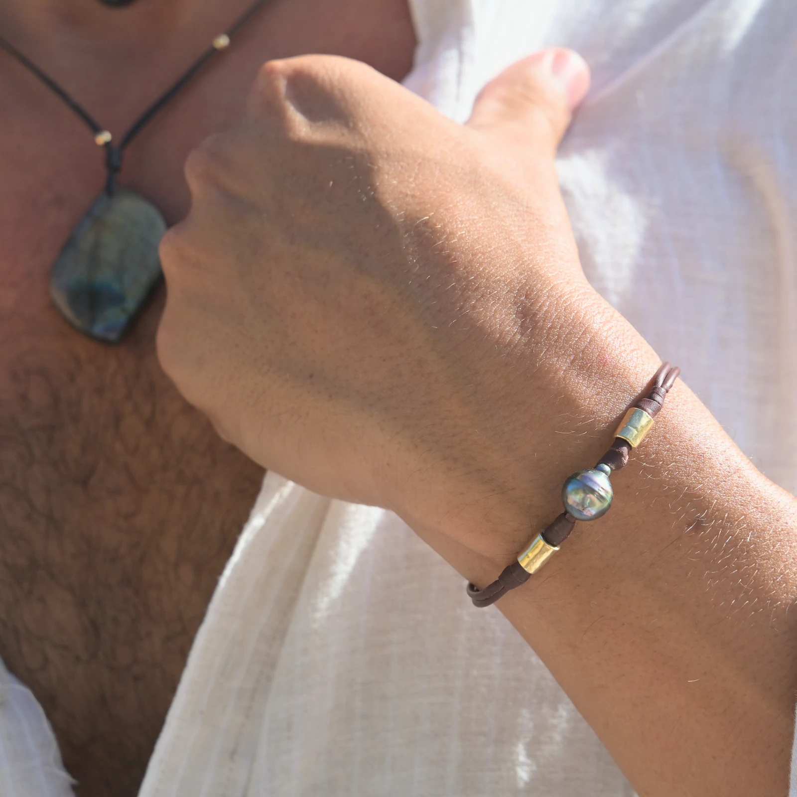 Double Leather Bracelet with a Tahitian Pearl and Gold-Plated Tubes, worn on the wrist.