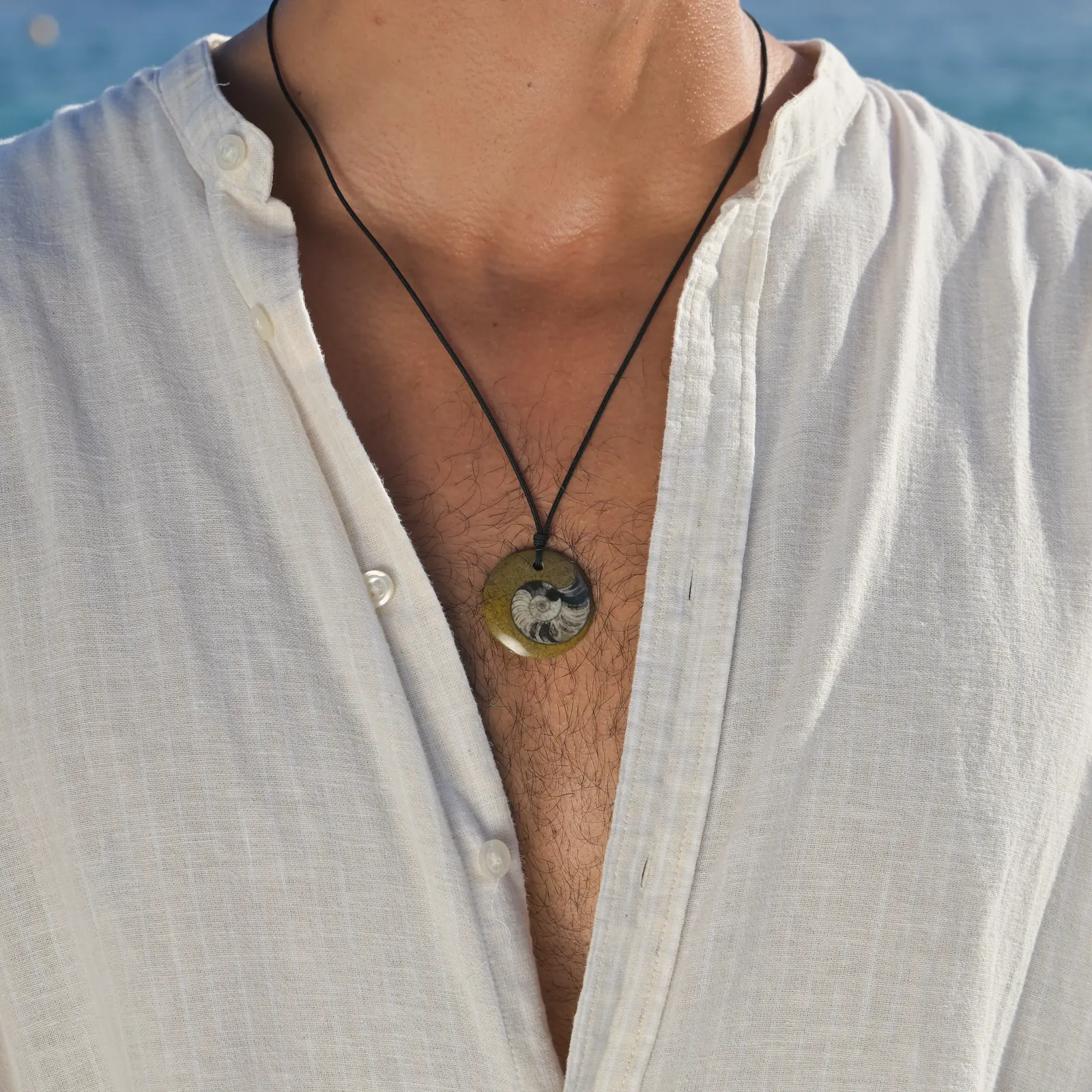 Collier ajustable avec fossile d’ammonite, porté au cou.