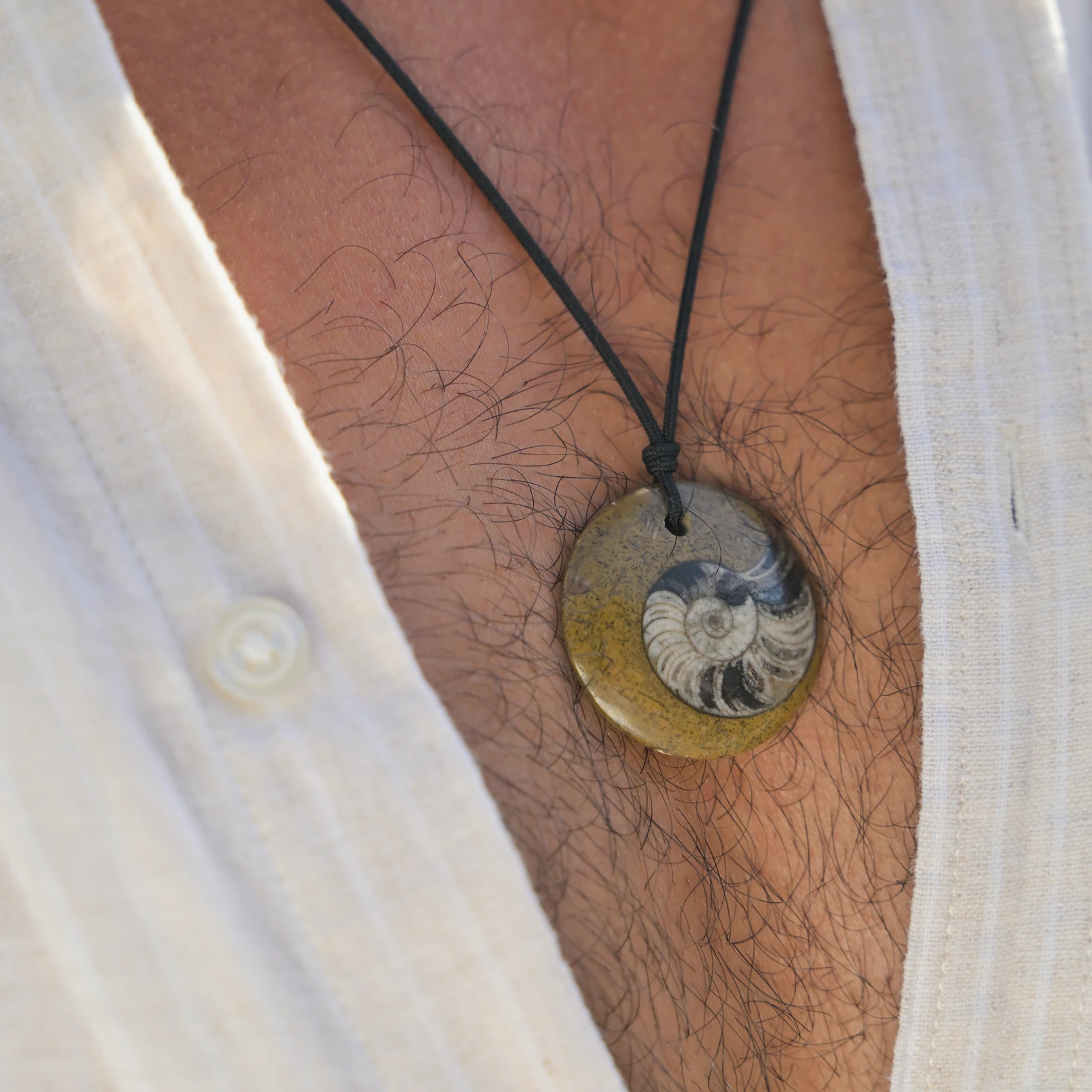 Collier ajustable avec fossile d’ammonite, porté au cou.