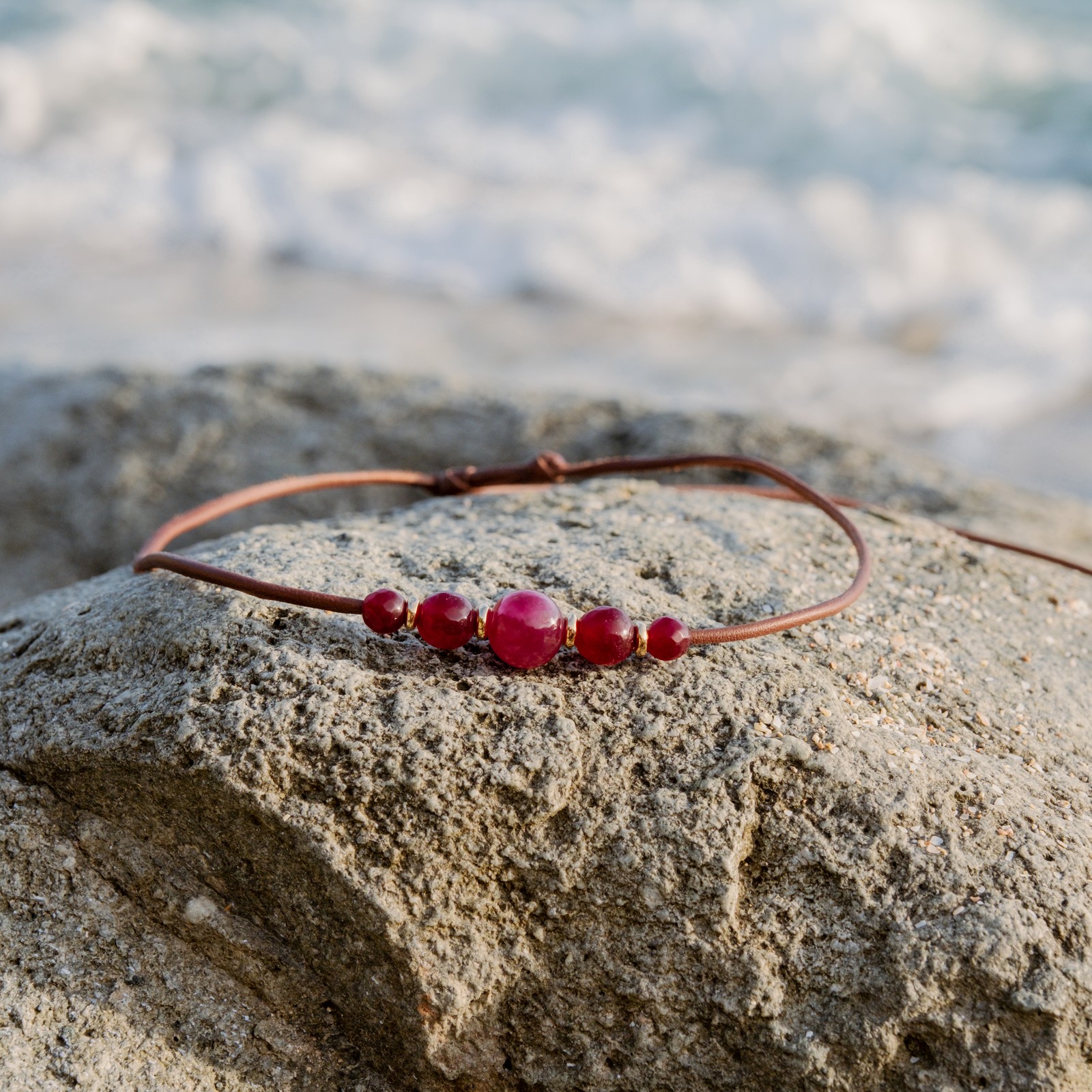 Collier ras du cou en cuir, cinq rubis et anneaux dorés, posé en ambiance naturelle