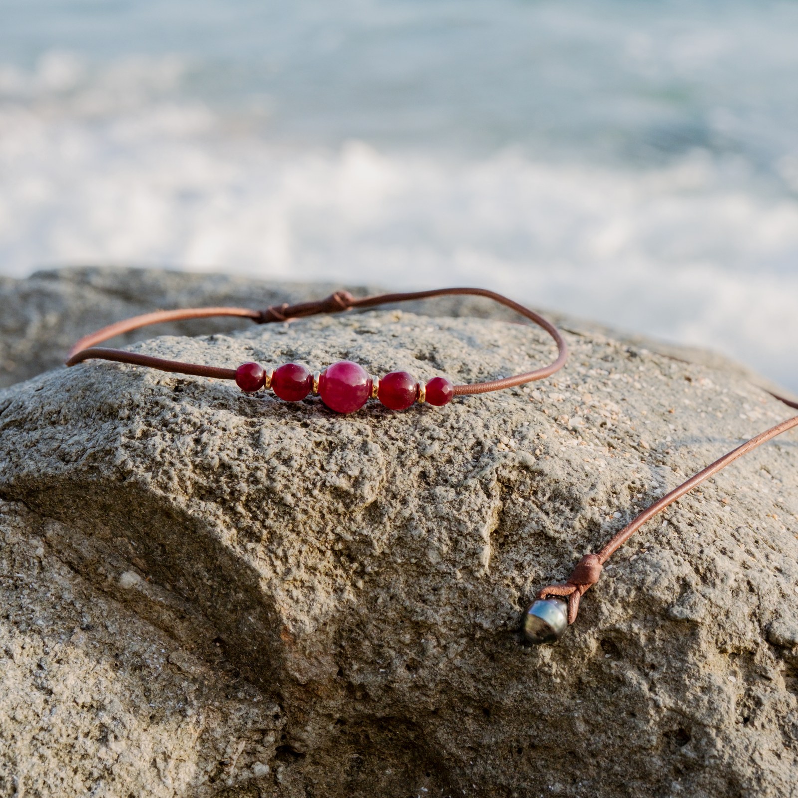 Collier ras du cou en cuir, cinq rubis et anneaux dorés, posé en ambiance naturelle