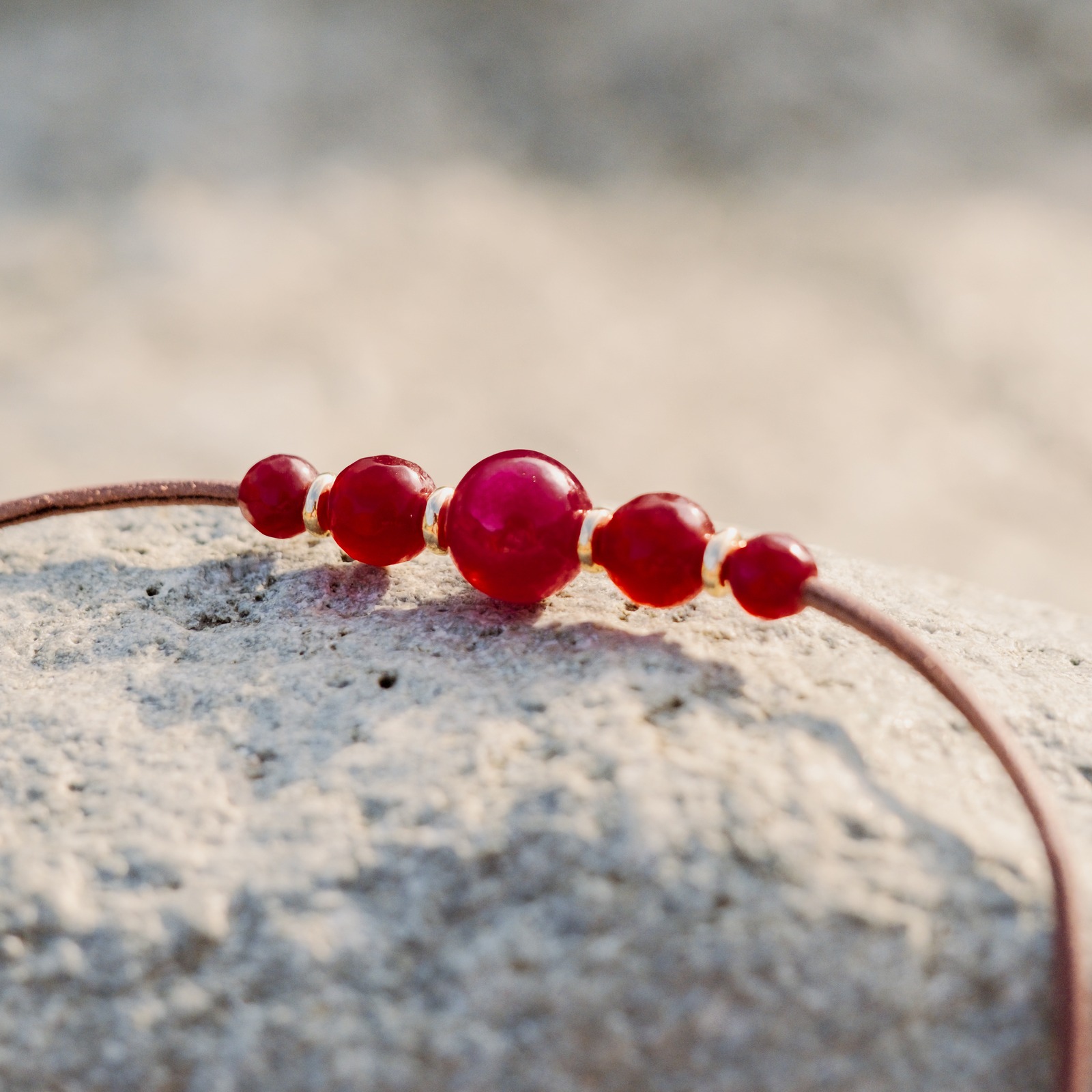 Collier ras du cou en cuir, cinq rubis et anneaux dorés, posé en ambiance naturelle