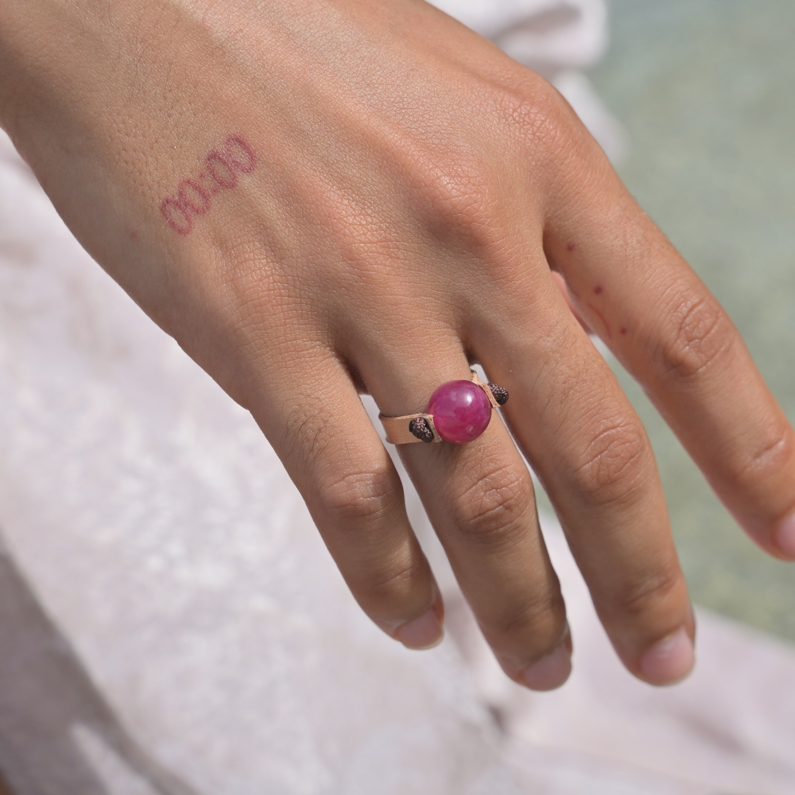 Bague en cuir et rubis, portée à la main