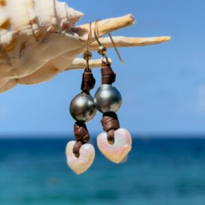 Boucles d’oreilles en cuir, cœurs en nacre et perles de Tahiti, posé en ambiance naturelle