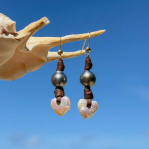 Boucles d’oreilles en cuir, cœurs en nacre et perles de Tahiti, posé en ambiance naturelle