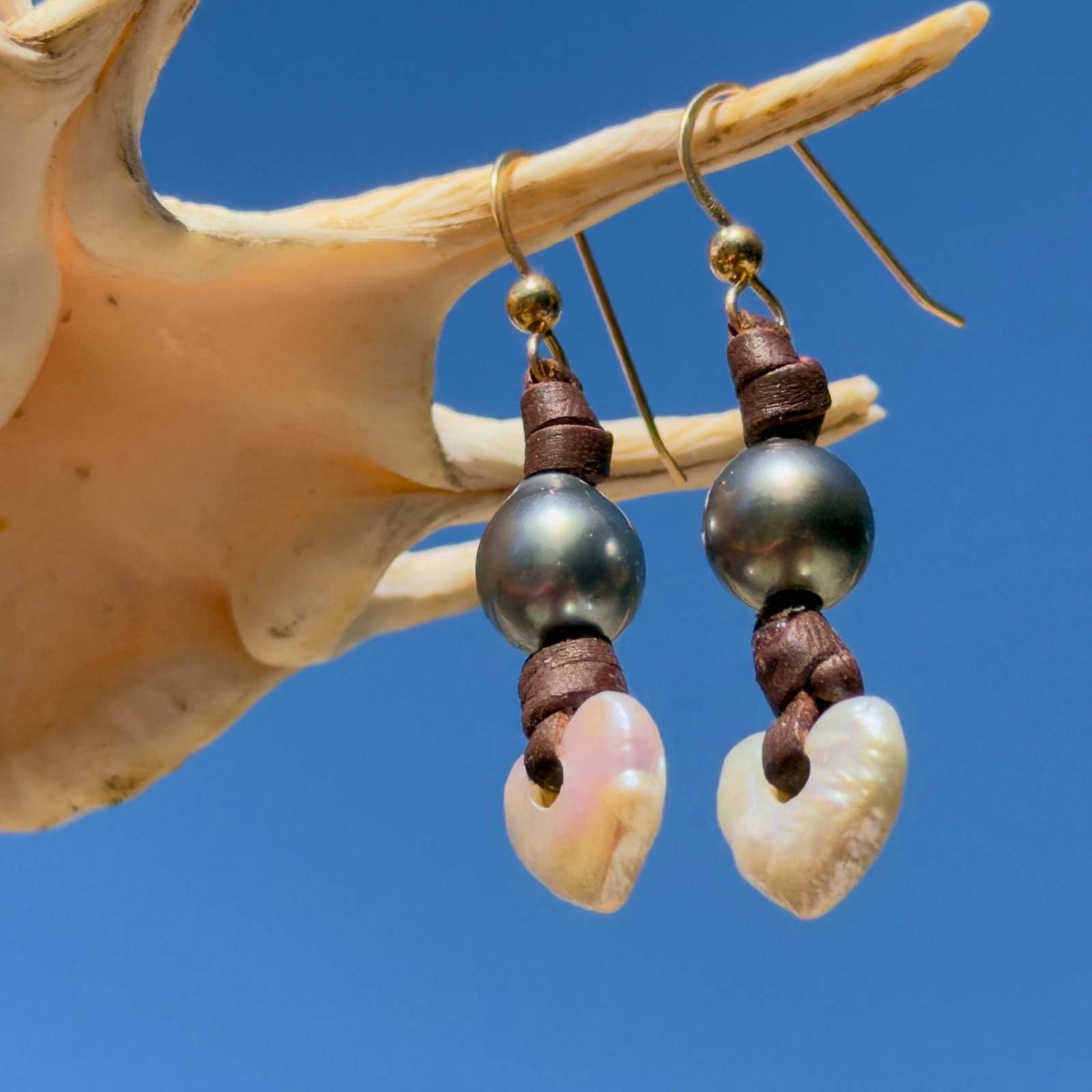 Boucles d’oreilles en cuir, cœurs en nacre et perles de Tahiti, posé en ambiance naturelle