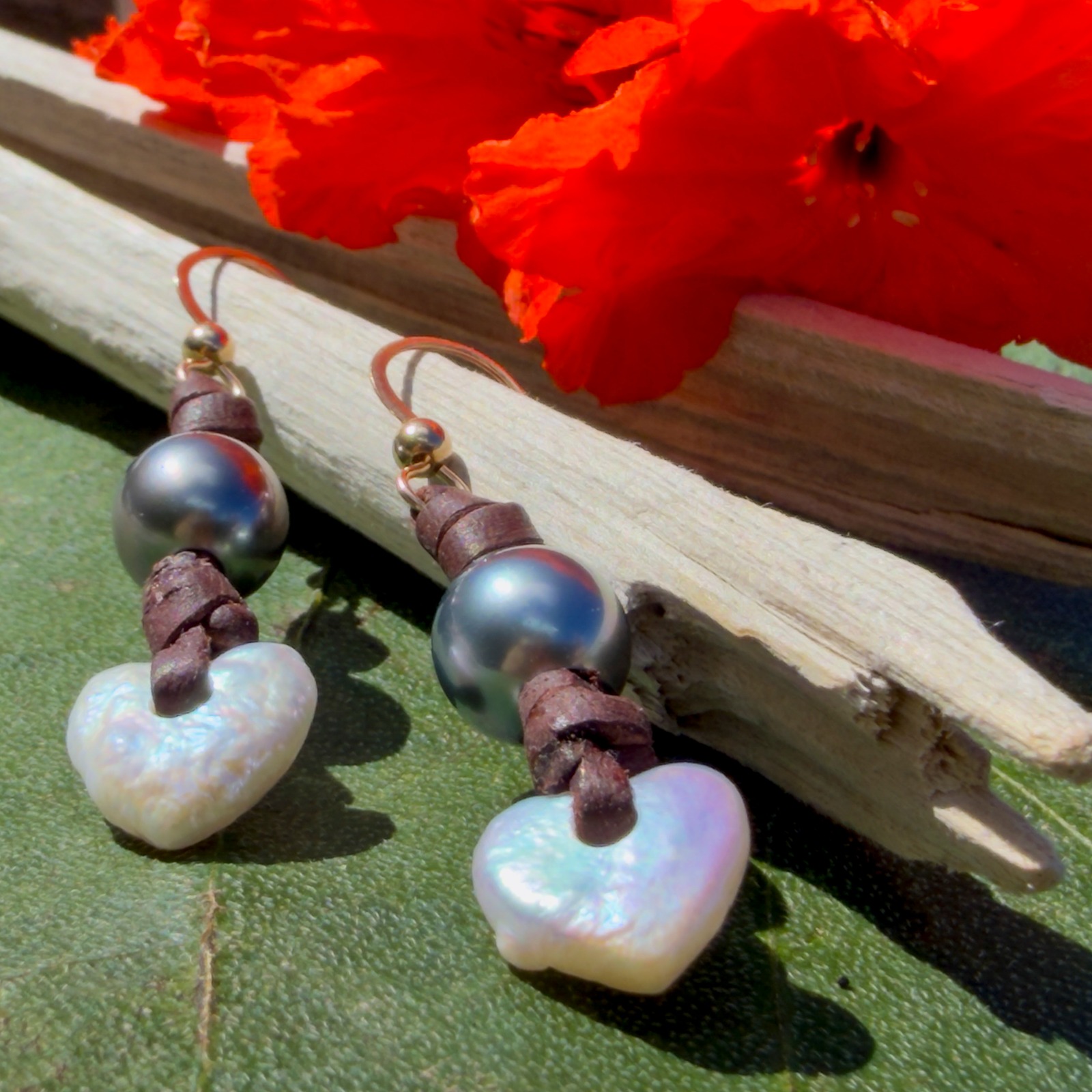 Boucles d’oreilles en cuir, cœurs en nacre et perles de Tahiti, posé en ambiance naturelle
