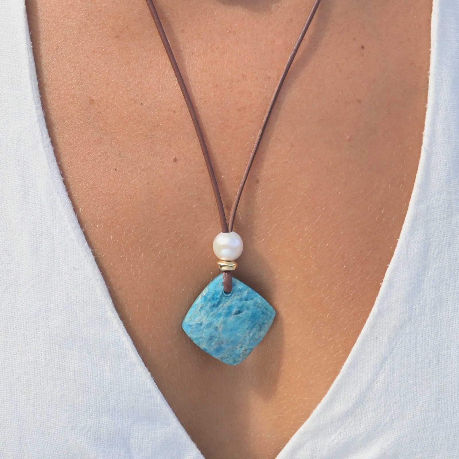 Collier en cuir, pendentif apatite et perle blanche, porté au cou