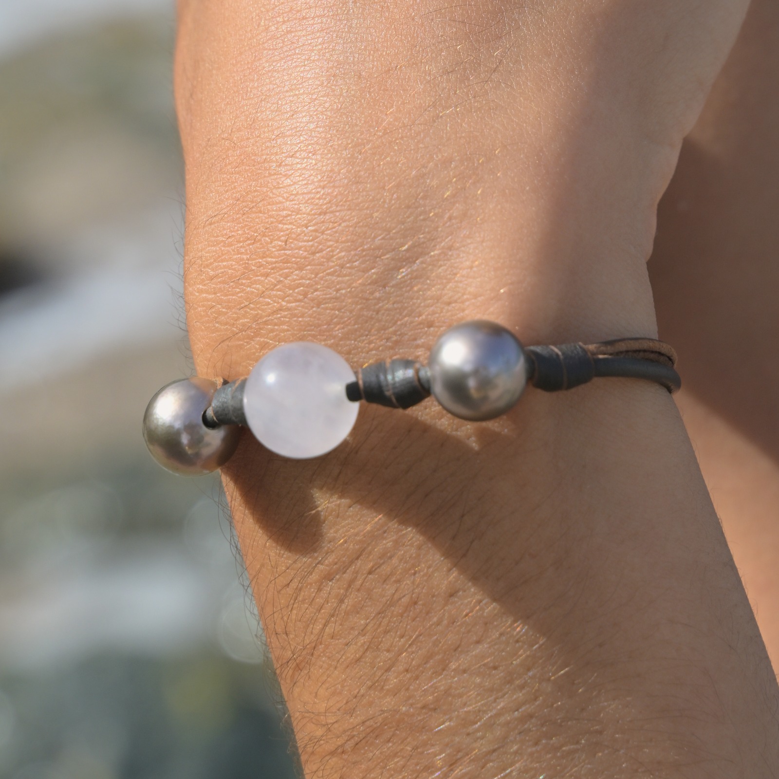 Leather bracelet with rose quartz between two Tahitian pearls, worn on the wrist