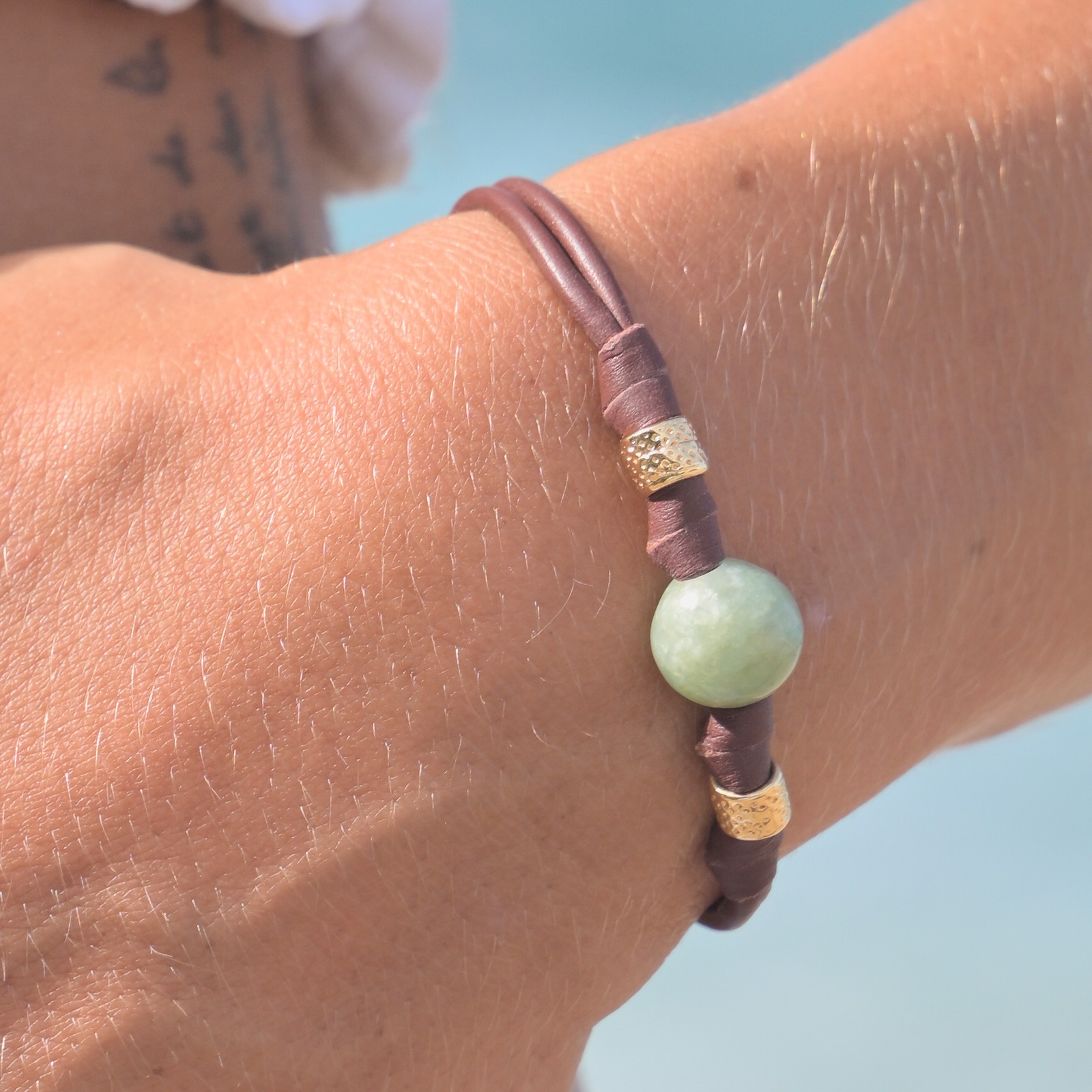 Bracelet en cuir, jade et tubes dorés, porté au poignet