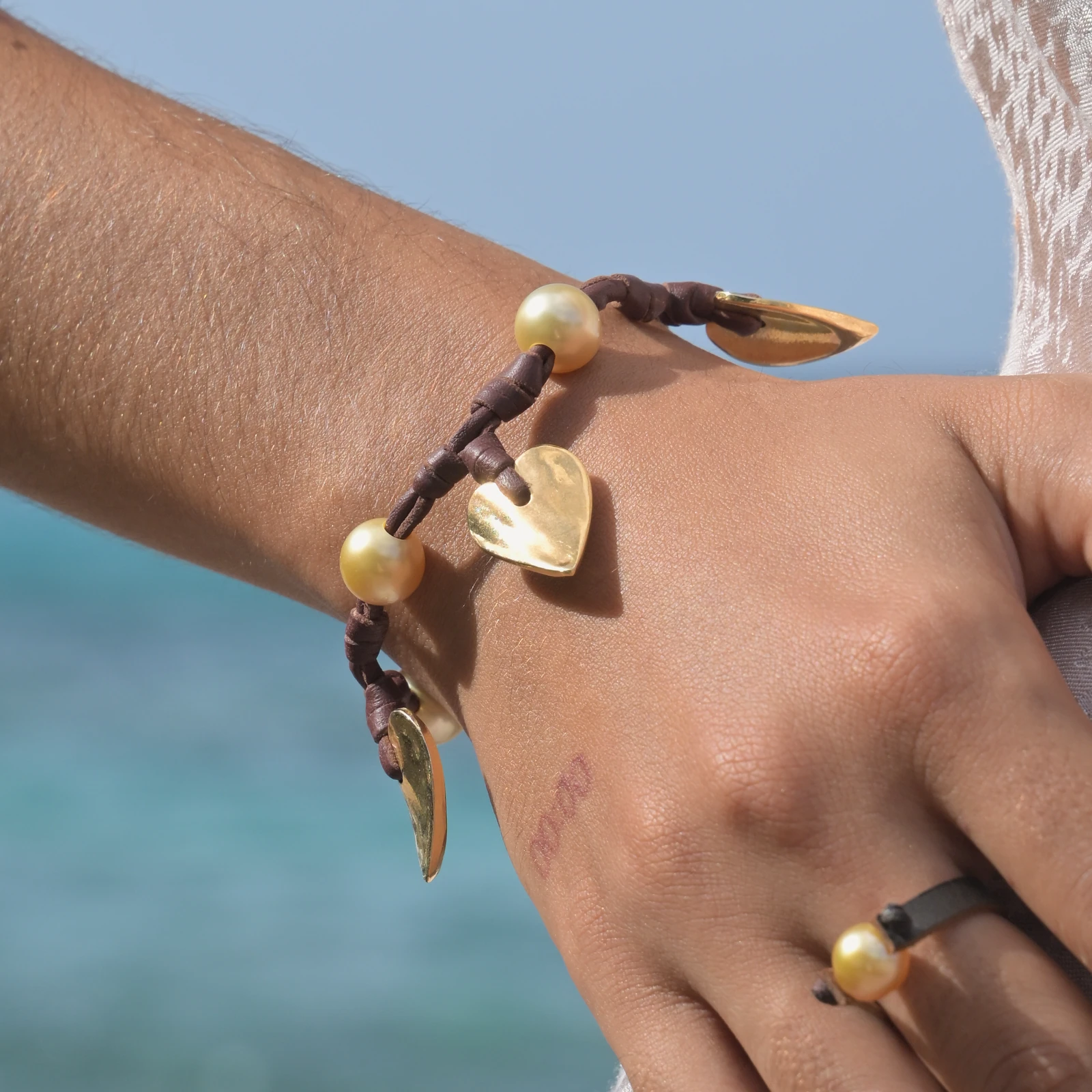 Valentine leather bracelet with hearts and golden pearls, worn on the wrist