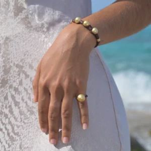 Leather bracelet with three golden pearls and golden tubes, worn on the wrist
