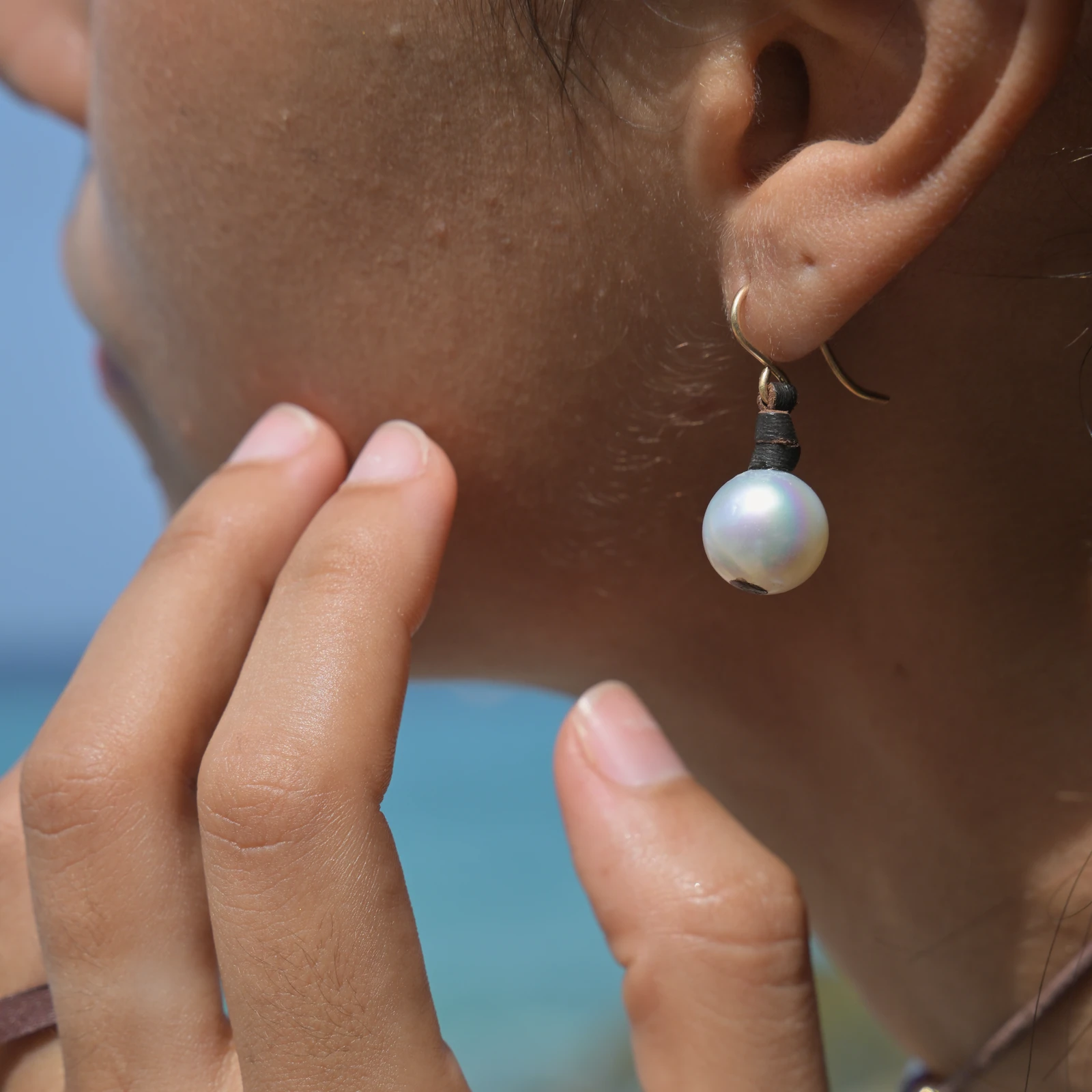 Classic leather earrings with cultured pearls, worn on the ears