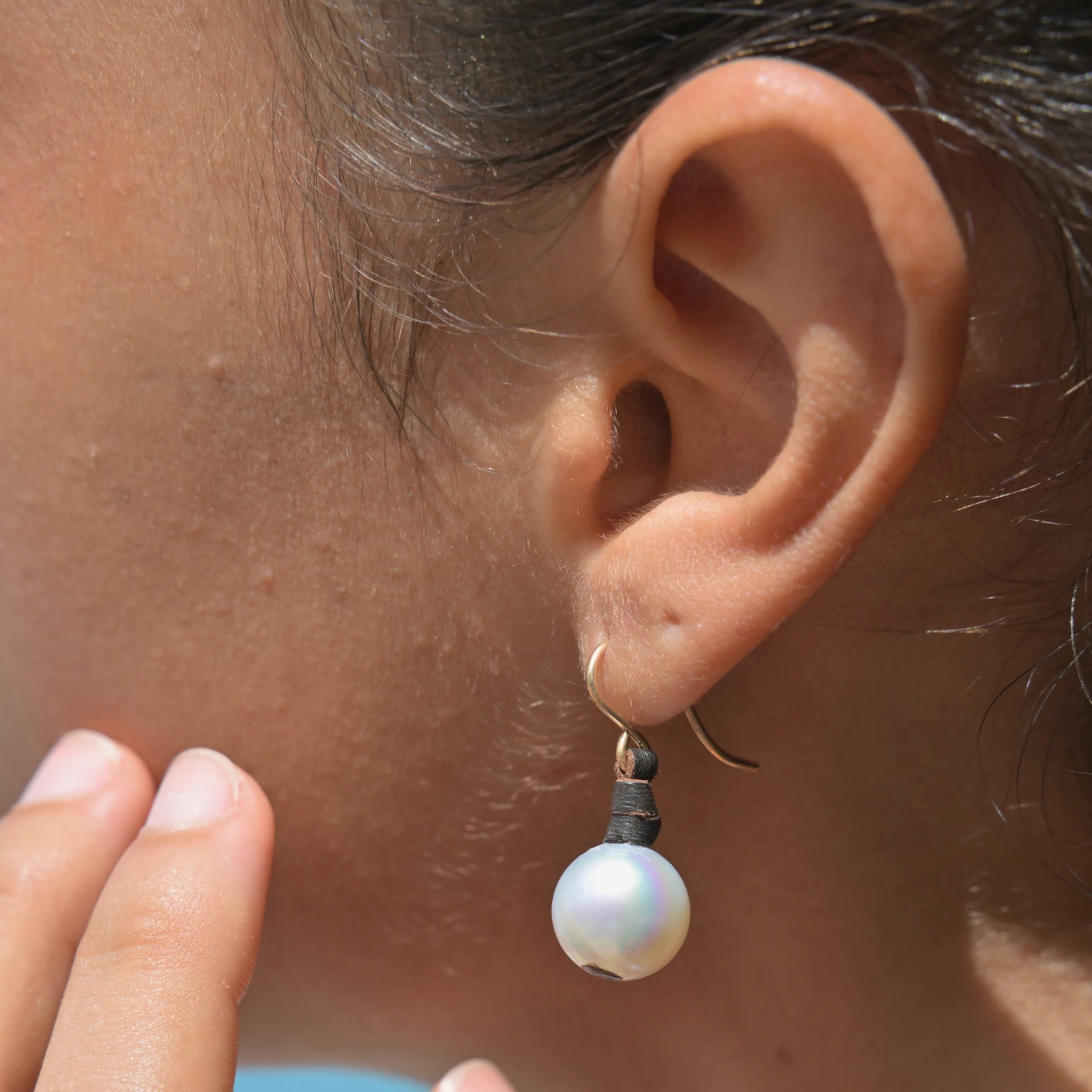 Classic leather earrings with cultured pearls, worn on the ears