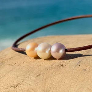 Collier ras du cou en cuir et trio de perles pastel, sur fond naturel