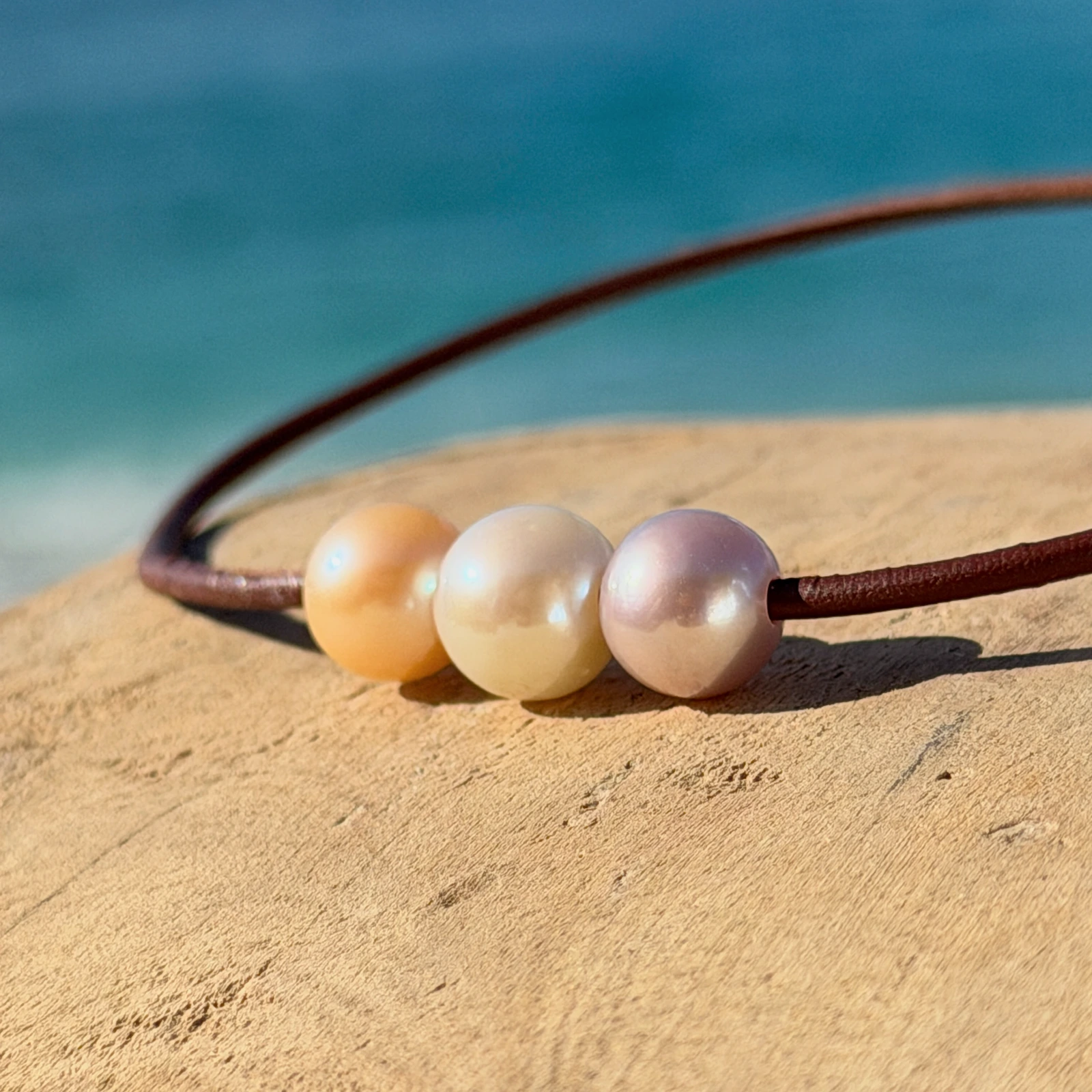 Leather choker with three pastel pearls, on a natural background