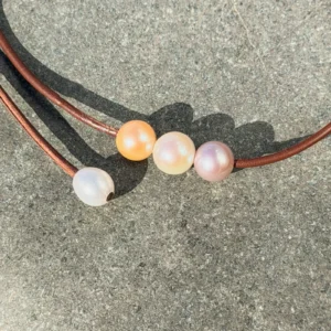 Collier ras du cou en cuir et trio de perles pastel, sur fond naturel