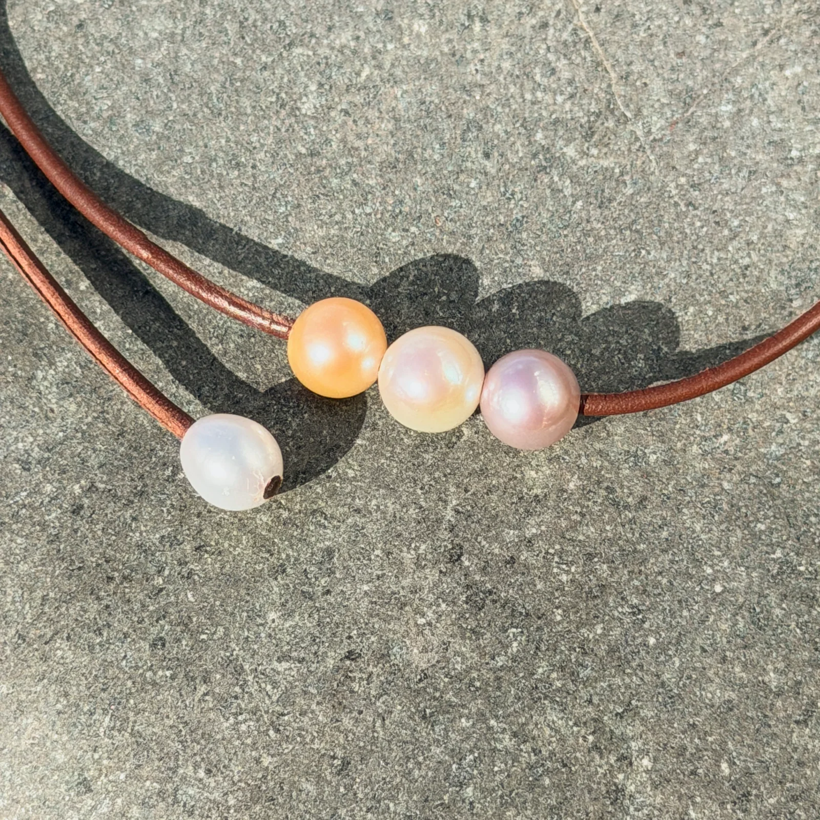 Leather choker with three pastel pearls, on a natural background