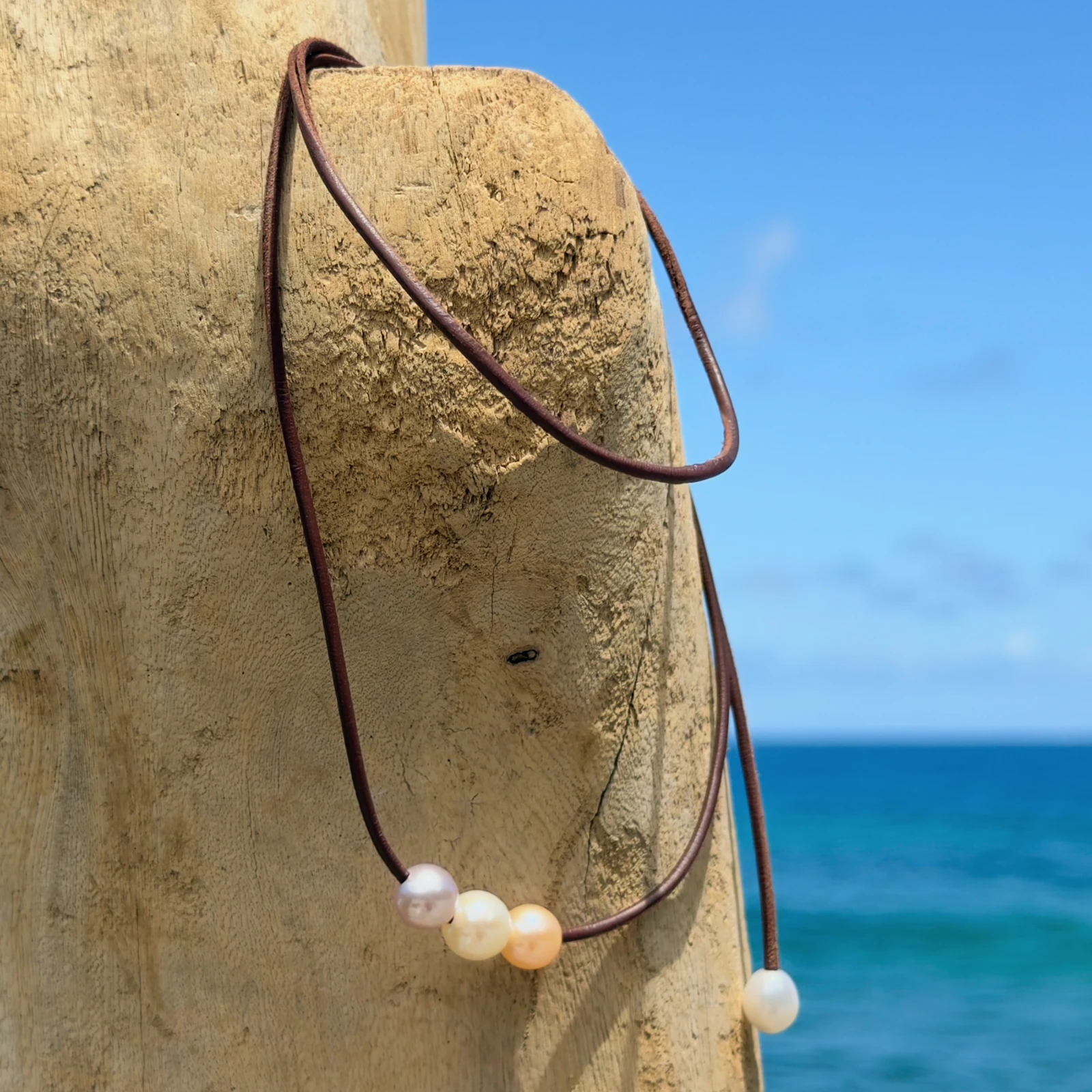 Leather choker with three pastel pearls, on a natural background