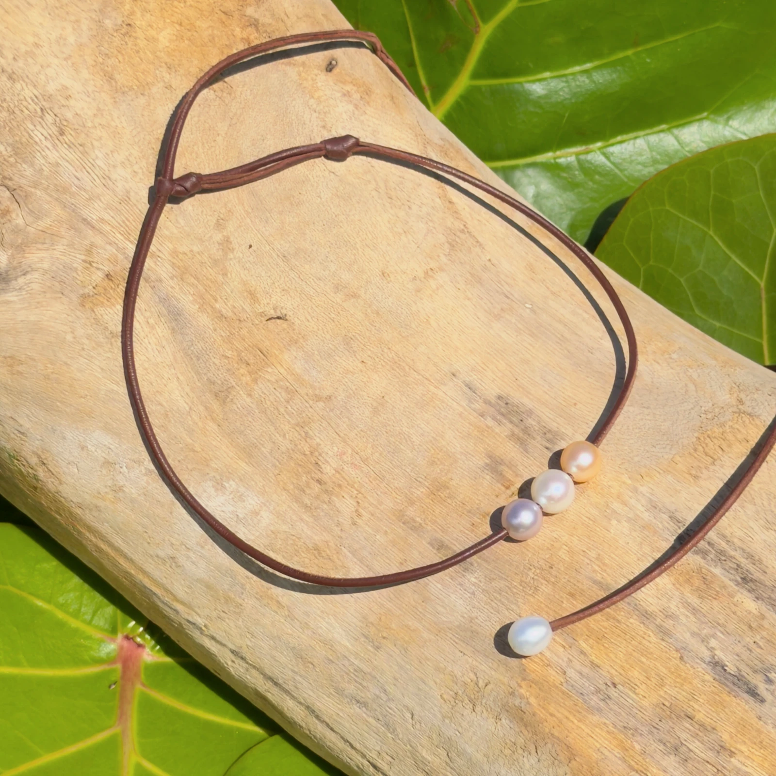 Leather choker with three pastel pearls, on a natural background