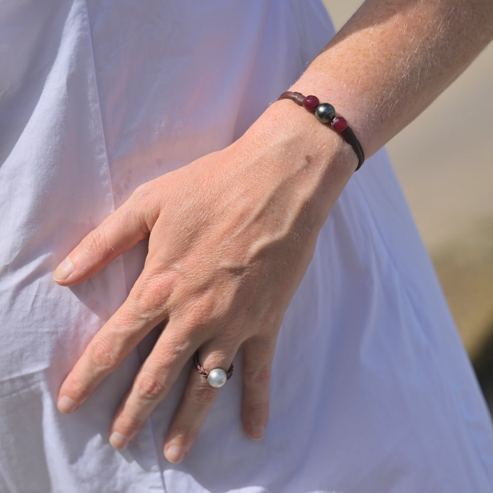 Bracelet en cuir, perle de Tahiti entre deux rubis, porté