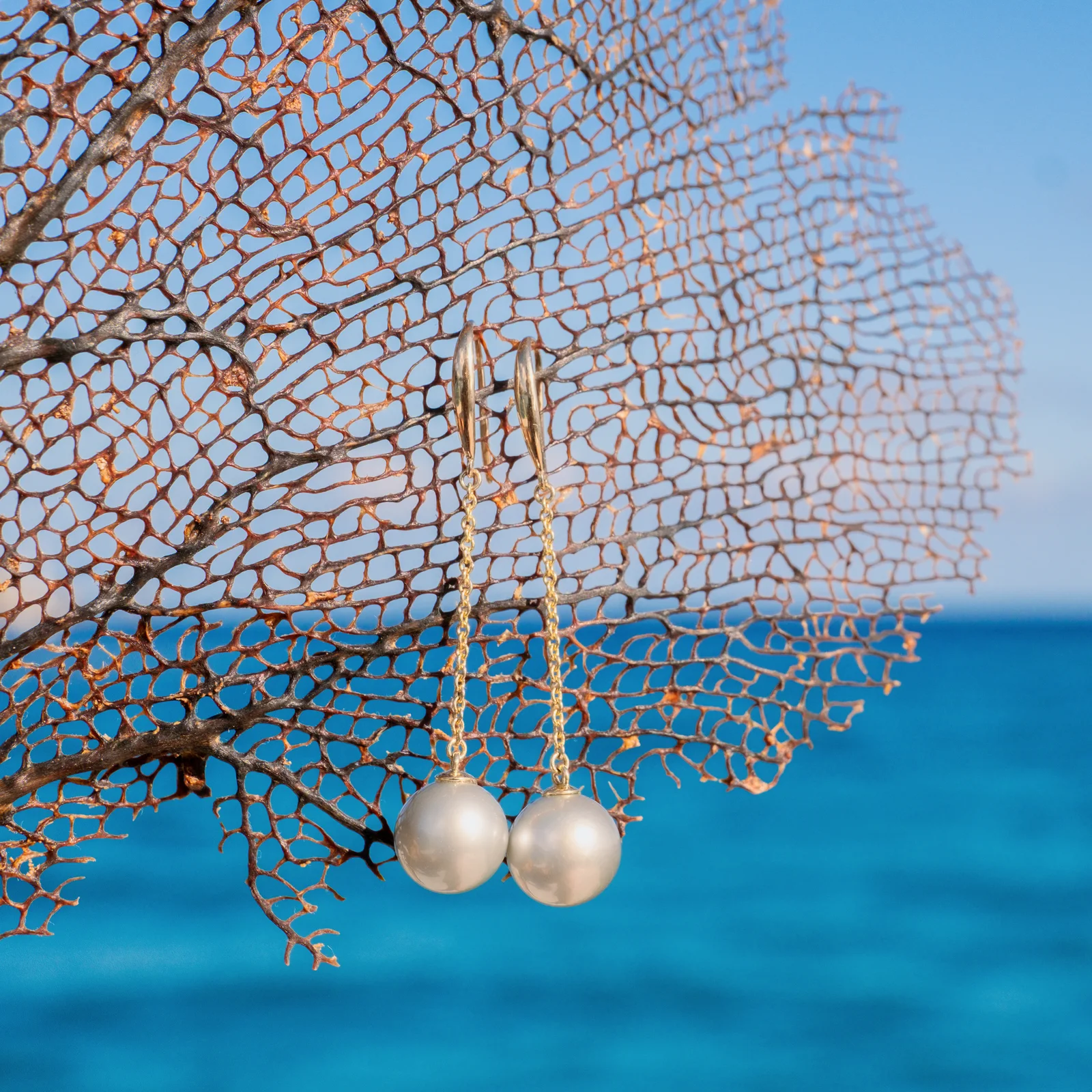Boucles d’oreilles longues sur dormeuses en or et perles au choix, sur fond naturel