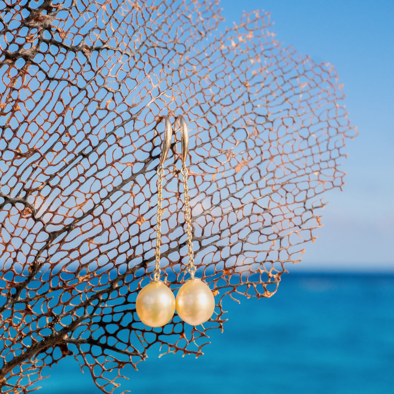 Boucles d’oreilles longues sur dormeuses en or et perles au choix, sur fond naturel