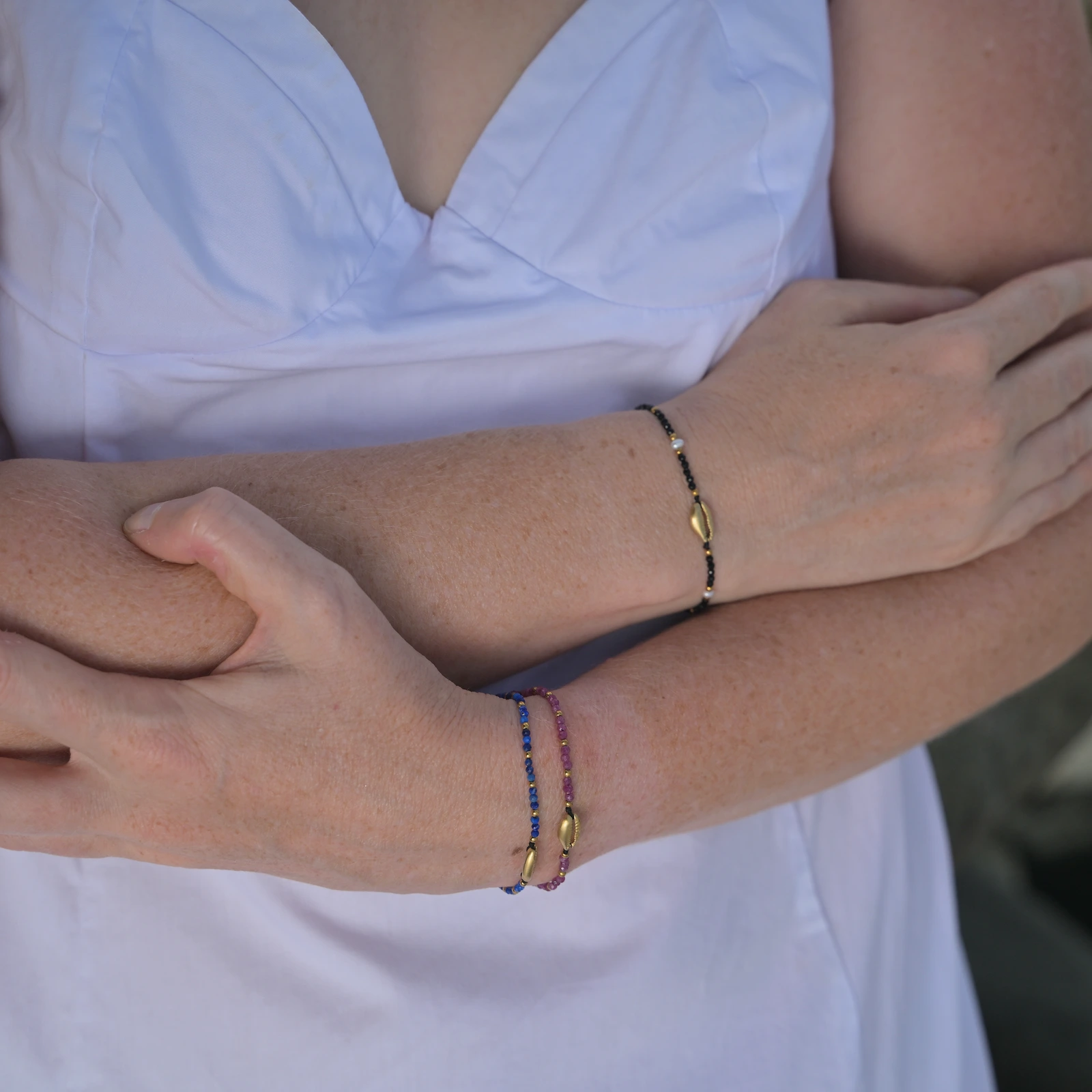 Adjustable bracelet with a gold-plated cowrie and faceted gemstones, worn