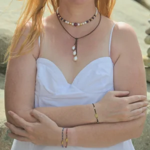 Adjustable bracelet with a gold-plated cowrie and faceted gemstones, worn