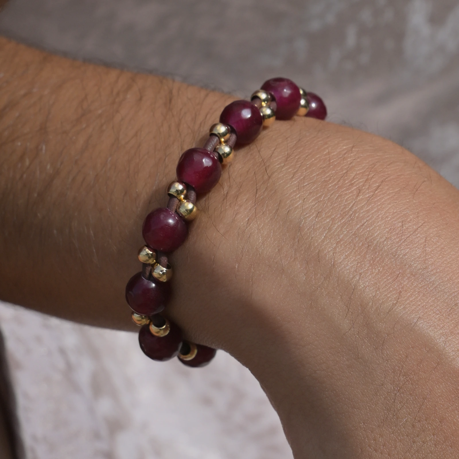 Faceted ruby bracelet with gold-plated beads and a South Sea pearl, worn