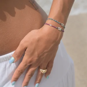 Adjustable bracelet with a sterling silver cowrie and small gemstones, worn