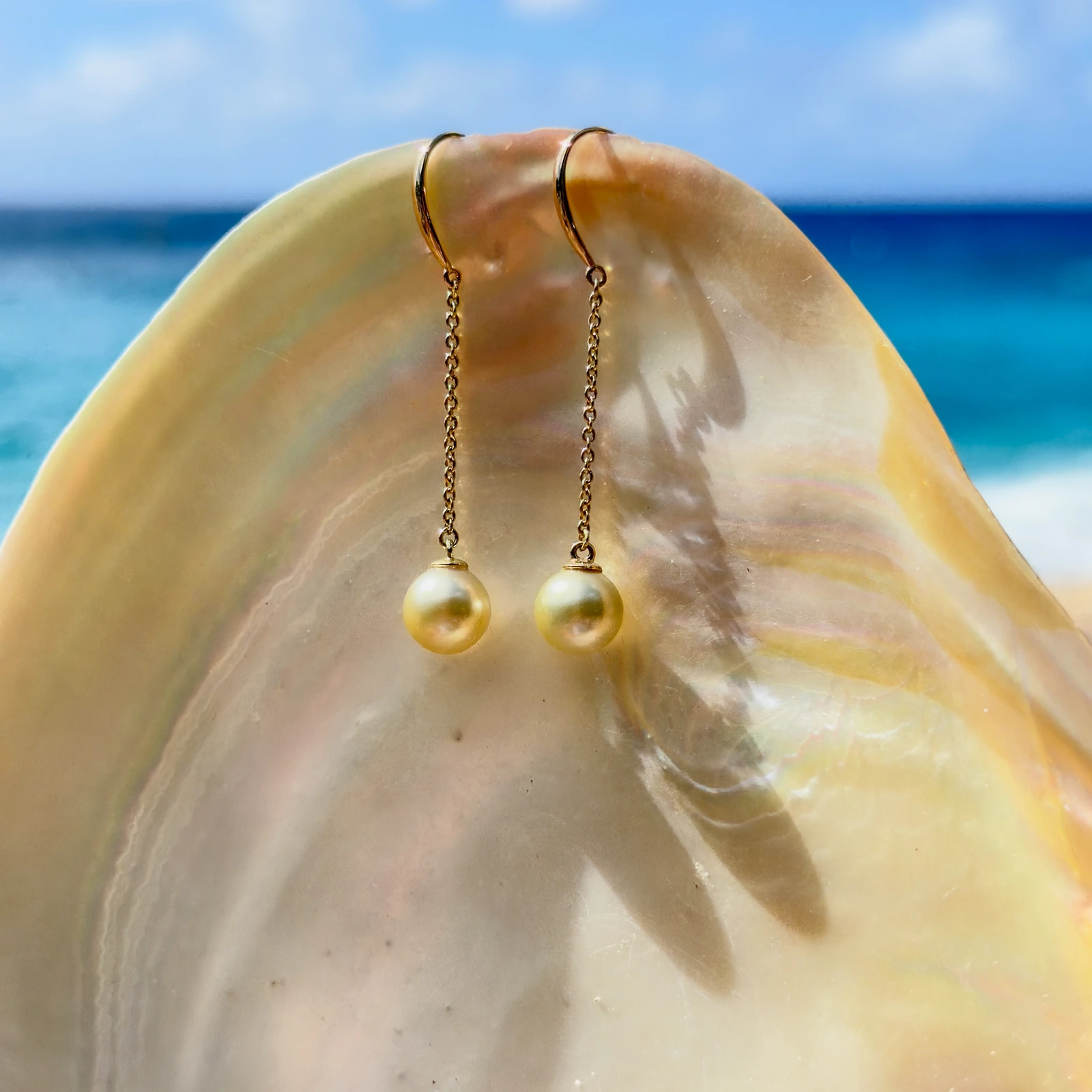 Long gold earrings with golden pearls, still-life view