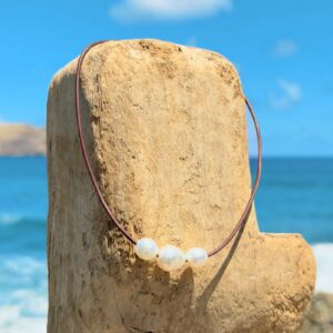 Collier ras du cou en cuir et trio de perles blanches baroques, bijou posé sur un fond naturel