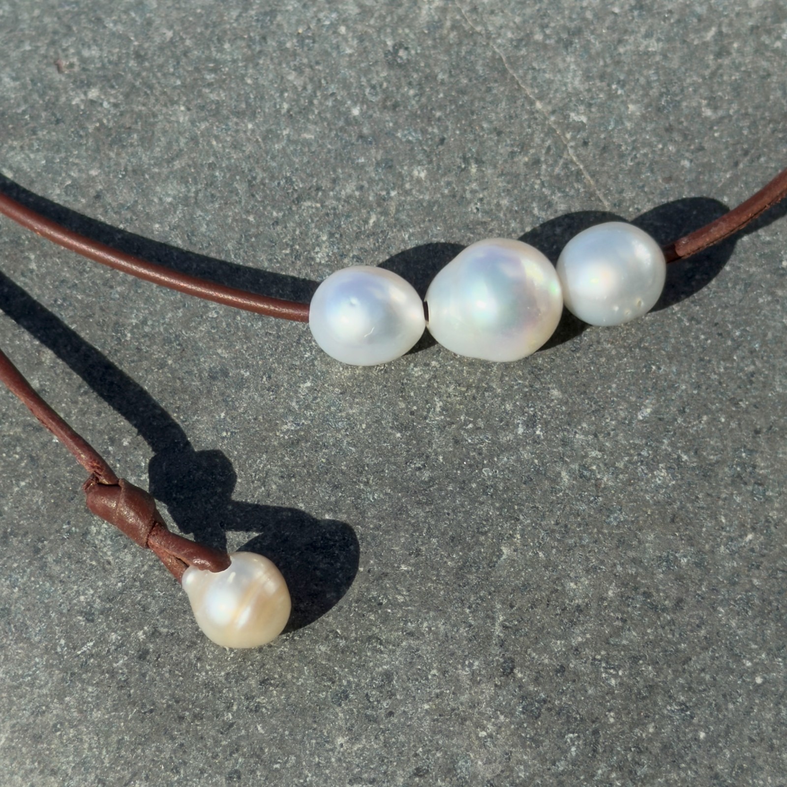 Collier ras du cou en cuir et trio de perles blanches baroques, bijou posé sur un fond naturel