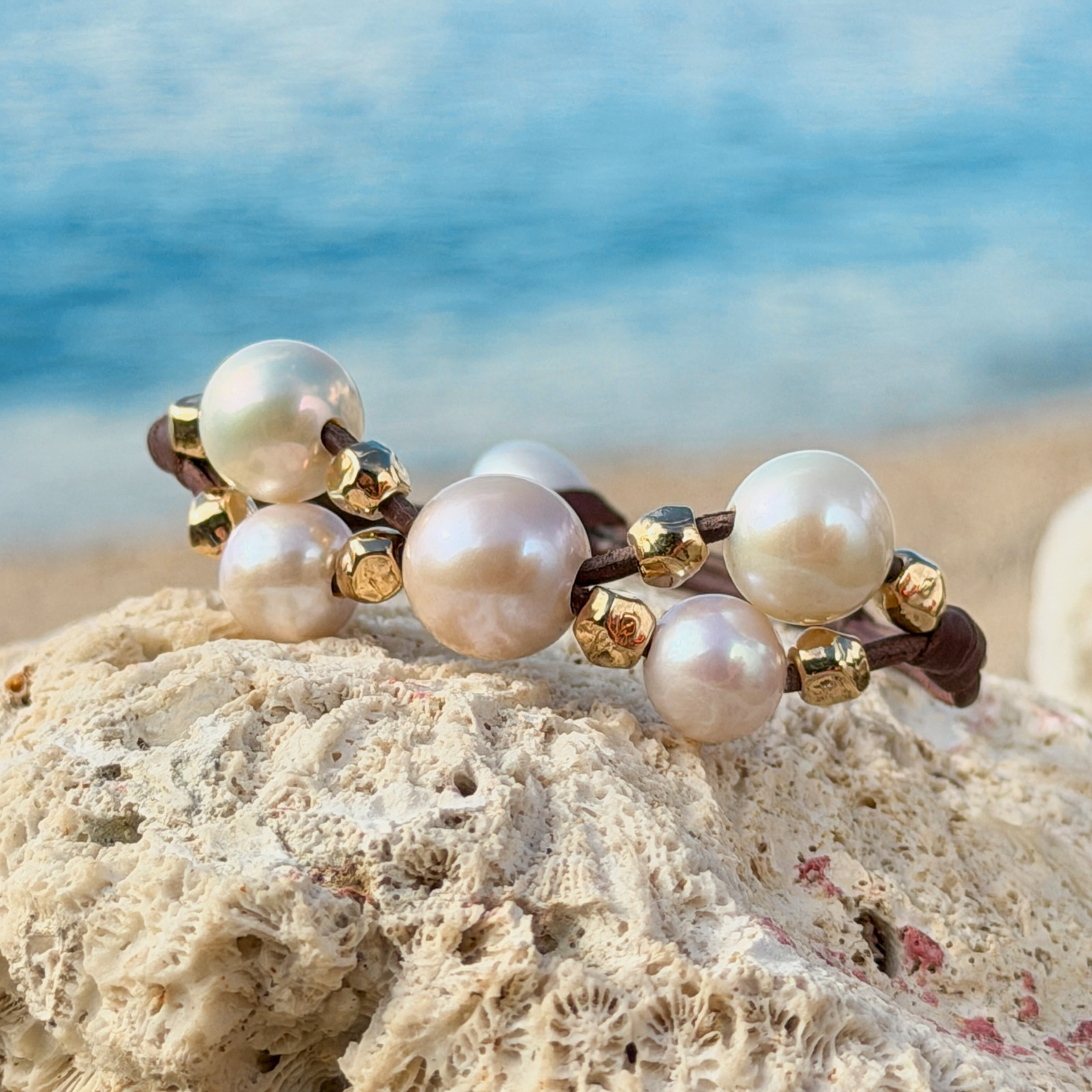 Bracelet Papillon en cuir, perles blanches et billes dorées, bijou posé sur un fond naturel