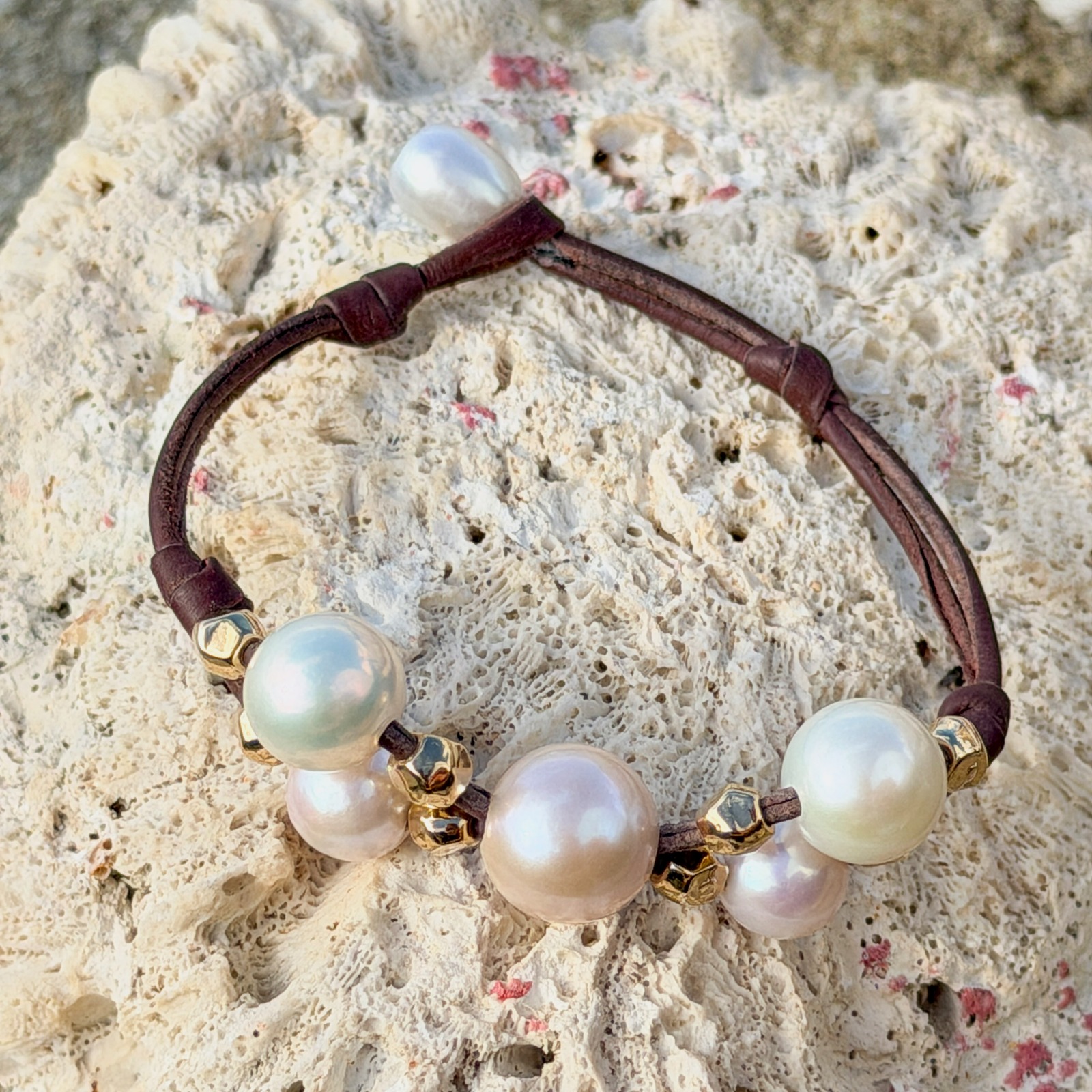 Bracelet Papillon en cuir, perles blanches et billes dorées, bijou posé sur un fond naturel